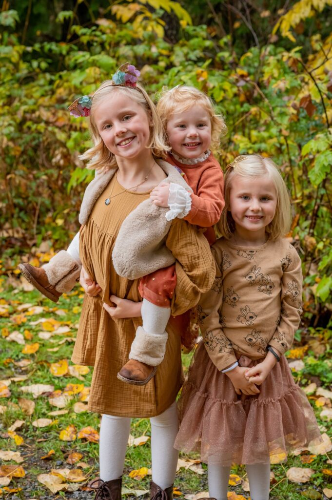 Family walking through autumn leaves during a fall photo session in Vancouver, BC